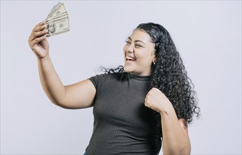 Victorious young woman holding money celebrating isolated. Excited latin girl holding dollar cash