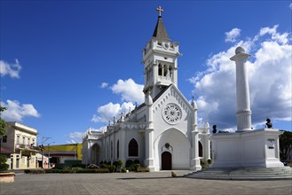 White church with pointed tower on a sunny square under a blue and white sky, Church of San Pedro