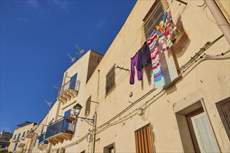 Morning light, row of houses, colourful houses, balconies, laundry on line, Levanzo town, main