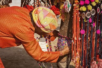 PUSHKAR, INDIA, NOVEMBER 22, 2012: Man decorating his camel for camel decoration contest at Pushkar