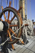 Steering wheel and ropes coiled around belaying pins aboard the Grand Turk, Etoile du Roy, a