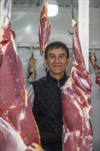 Butcher looking through hung meat, butcher's shop, at the market stall for meat products, Uzgen