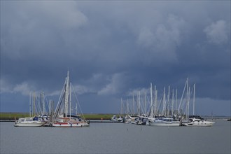 Sailing ships lying in the marina, dark clouds over the sea, Norddeich, Norden, North Sea, East