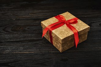 Gift birthday Christmas present concept, gift box with red ribbon on dark wooden background