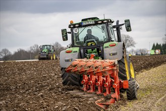 Tractor with a plough preparing the soil of a field for planting, Agriculture, Spring