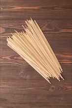 Japanese buckwheat soba noodles on brown wooden background. Top view, flat lay, copy space