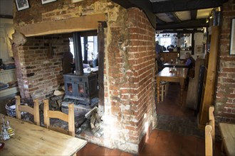 Fireplace customers at tables inside public bar of White Lion pub, Ufford, Suffolk, England, UK