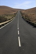 Tarmac road crossing barren desert mountainous land between Pajara and La Pared, Fuerteventura,