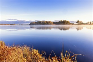 Glossy lake with water reflections and mist a scenics autumn morning in the nordic wilderness,