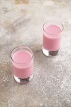 Sweet strawberry liqueur in glass on a gray concrete background. Side view, close up