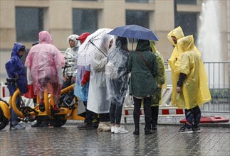 Tourists protect themselves from heavy rainfall with rain capes and umbrellas, Berlin, 23 06 2023