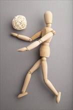 Wooden mannequin playing football on gray pastel background. copy space, isolated, sports concept