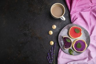 Sweet tartlets with jelly and milk cream with cup of coffee on a black concrete background and pink