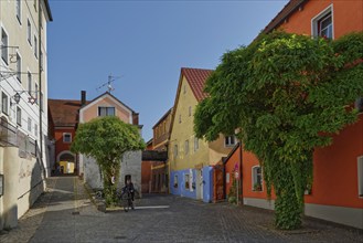 Person riding a bicycle on the Vils alley with historic buildings and cobblestones, Kallmünz, Upper