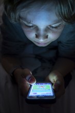 A boy plays computer games on a mobile phone, smartphone