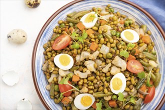 Mung bean porridge with quail eggs, tomatoes and microgreen sprouts on a white concrete background