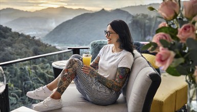 Relaxed woman with tattoos enjoys her drink with a view of a mountain panorama, AI generated, AI