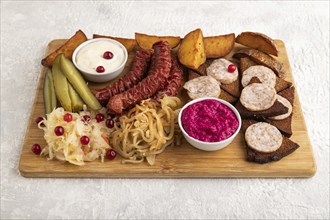 Set of snacks: sausages, toast, sauerkraut, marinated onion and cucumber, baked potato on a cutting