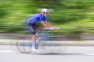 Cyclist in blue jersey riding fast on a road, movement and speed blur the image, race, Stuttgart,