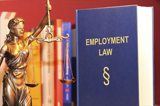 Symbolic image: Reference book Employment law (labour law) and a Justitia