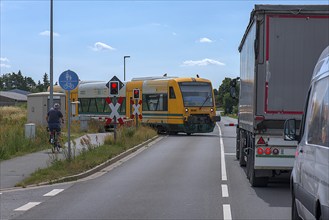 Suburban railway crossing the gated level crossing, Rehna, Mecklenburg-Western Pomerania, Germany,