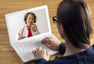 Symbolic image of telemedicine, patient speaking to a doctor in a video conference from home