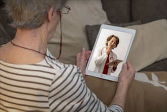 Symbolic image of telemedicine, patient speaking to a doctor in a video conference from home