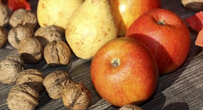 Apples, pears and walnuts on a rustic wooden table as an autumnal motif