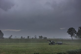 A farmer drives slurry onto a meadow with his tractor in the rain, storm, thunderstorm, Schlehdorf,