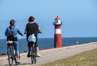 North Sea dyke near Westkapelle, Westkapelle Laag lighthouse, cyclists on the Zeeuwse Wind Route