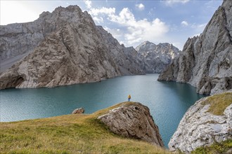 Tourist at the blue mountain lake between rocky steep mountain peaks, Kol Suu Lake, Sary Beles