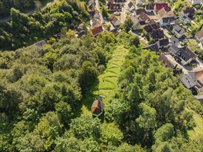 A cemetery on a hilly wooded area next to a village seen from the air, Gundringen, Nagold, Black