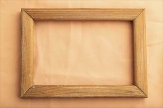 Wooden frame on smooth orange linen tissue. Top view, flat lay, natural textile background and