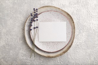 White paper invitation card, mockup with lavender on ceramic plate and gray concrete background.