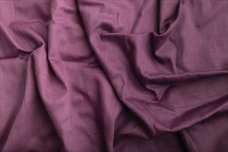 Fragment of cotton purple tissue. Top view, natural textile background and texture. wave concept,