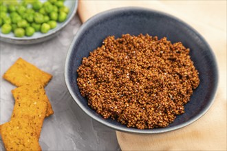 Raw quinoa in ceramic bowl on a gray concrete background and orange textile. Side view, close up