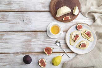 Summer appetizer with pear, cottage cheese, figs and honey on a white wooden background and linen