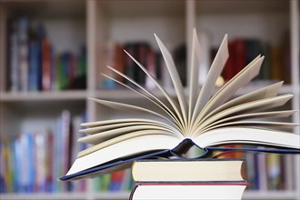 Close-up of an open book, behind it a blurred bookshelf