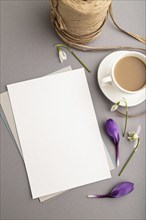 White paper sheet mockup with spring snowdrop crocus and galanthus flowers and cup of coffee on