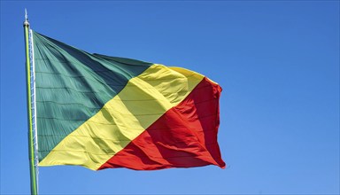 The flag of Congo flutters in the wind, isolated against a blue sky