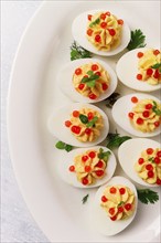 Stuffed eggs, with red caviar, micro greenery, Snack, on a white plate, top view, close-up, no