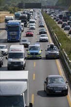 Police patrol car with flashing blue lights and siren working its way through a traffic jam on the