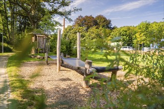 Wooden bridge on a playground surrounded by lush greenery and clear blue sky, Nagold, Black Forest,