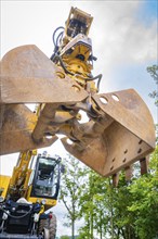 Shovel of an excavator on a construction site under a cloudy sky, track construction, Hermann