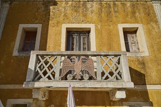 Traditional building with balcony and eagle motif, characterised by yellow colour, Colourful