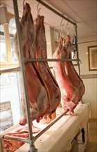 Whole lambs hanging from hooks inside a traditional butcher's shop, Marlborough, Wiltshire,