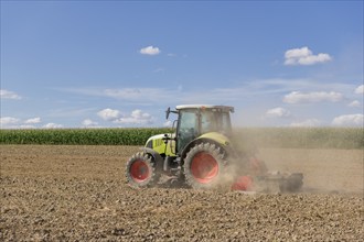 Symbolic image, global warming, dry soil, dust, farmer tilling a field, tractor, ploughing, clouds,