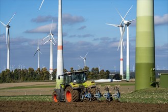 Farmer working in the fields, with a tractor, wind farm above the village of Lichtenau,