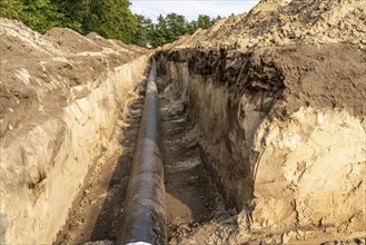 Laying of district heating pipes, next to a field, with maize, the district heating comes from a