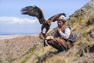 Traditional Kyrgyz eagle hunter with eagle in the mountains, near Kysyl-Suu, Kyrgyzstan, Asia